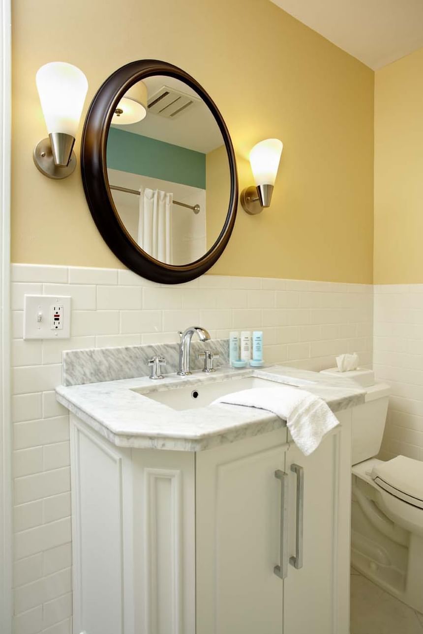 Bathroom vanity with wall-mounted round mirror in Max Villas at Breezeway Boutique Hotel