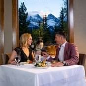 Couple sitting at an elegantly set dining table during one of the top Canmore events in Spring Creek Resorts