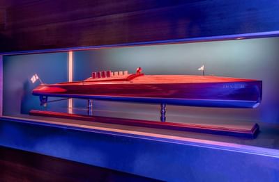 Detailed wooden model of a boat displayed inside a glass case with accent lighting at Harborside Inn Boston