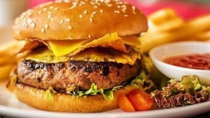 A cheeseburger with lettuce and tomatoes, fries, and ketchup served on a plate in Pendas Cafe at Sunway Hotel Big Box