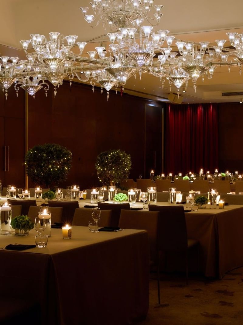 Chandeliers above a dining room with tables and chairs set for private dinner at The Crystal Ballroom at The May Fair Hotel, London.