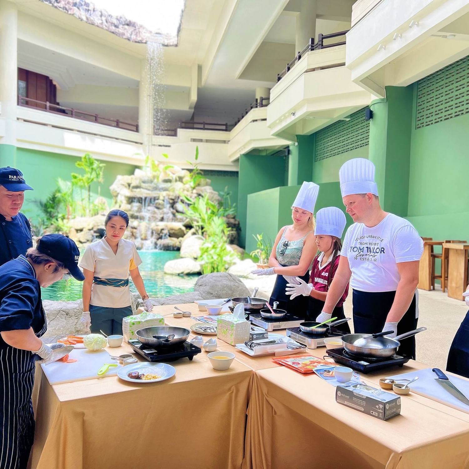 Chef at Paradox Resort Phuket guiding a family of four during a private Thai Cooking Class at a family-friendly hotel on Karon Beach.