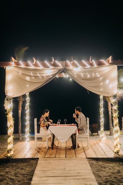 Couple having a romantic dinner by the beach near Playa Blanca Beach Resort at night