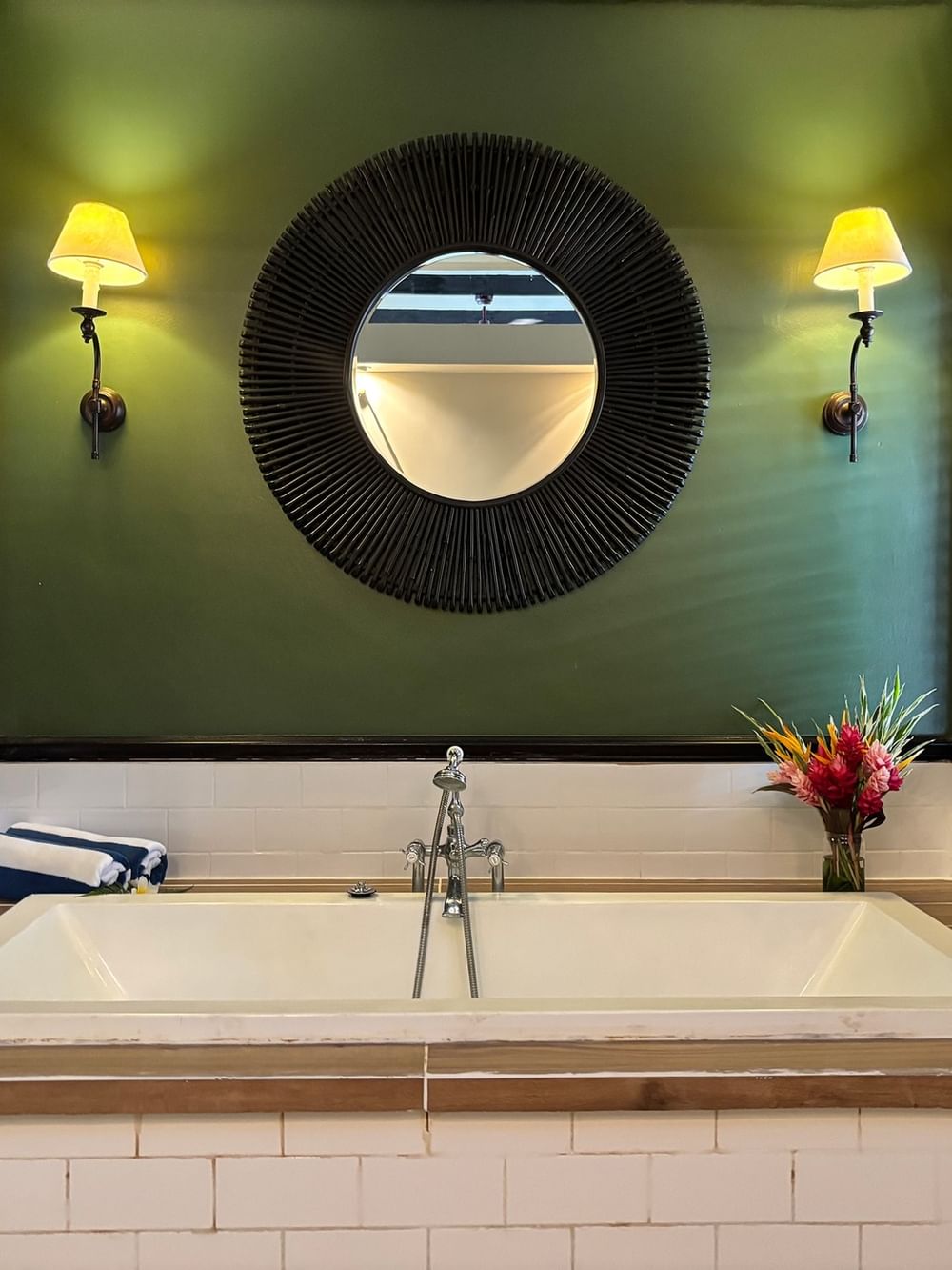 Green bathroom with a large bathtub, mirror, and tropical flowers at Warwick Le Lagon - Vanuatu, Efate.