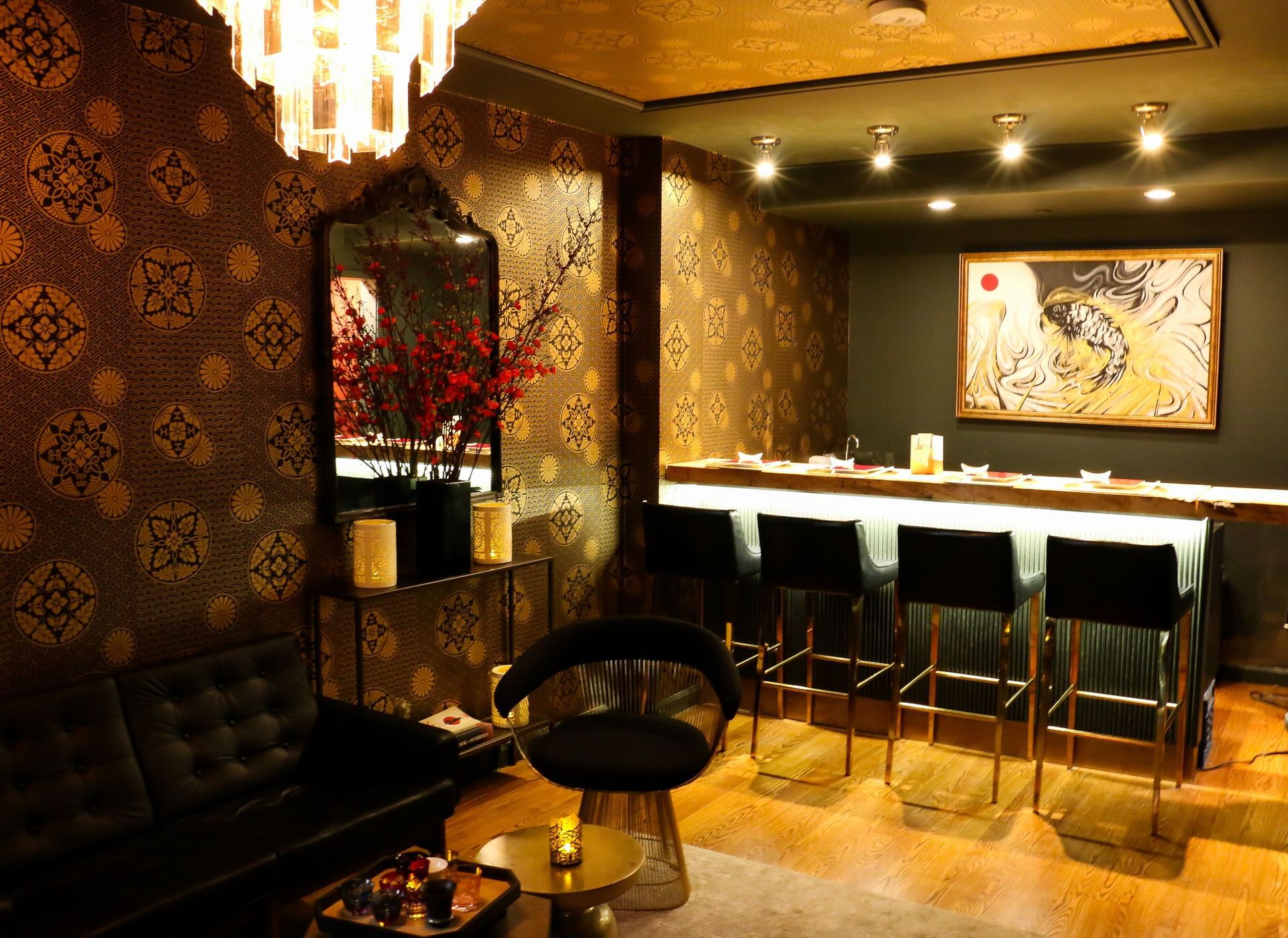 A dimly lit lounge with a bar, sofa, and chandelier.