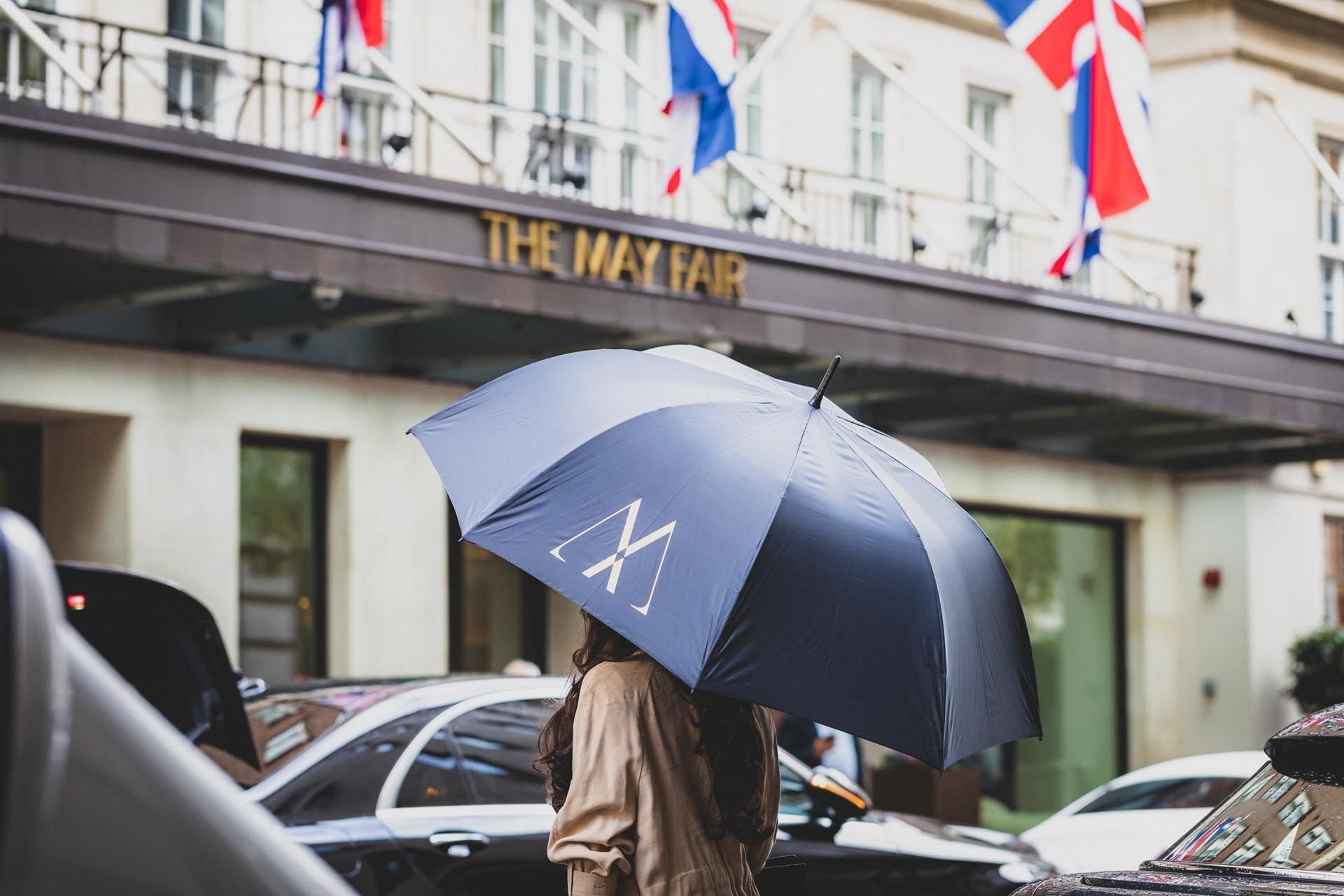 A girl holding an umbrella near The May Fair Hotel London