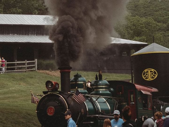 Steam engine train surrounded by people in Tweetsie Railroad near The Embers Hotel