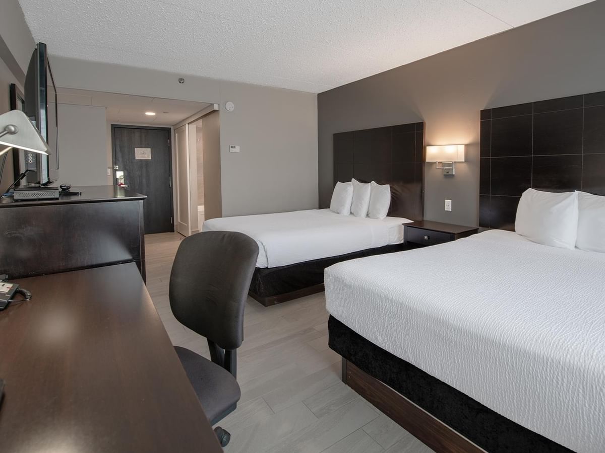 Two beds, desk, and chair in a hotel room.