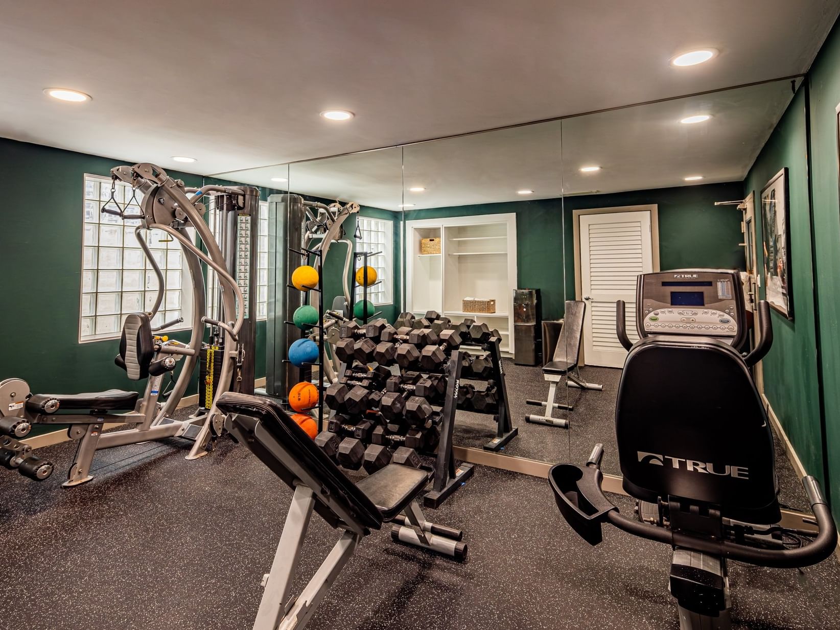 Fitness center with weight racks, exercise machines, and green walls at Clinton Hotel South Beach in Miami Beach.