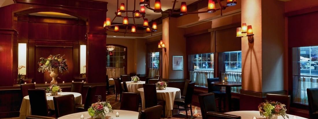 Pre-Function Meeting Room featuring round tables with white cloths & dark chairs and hanging chandeliers at Warwick New York