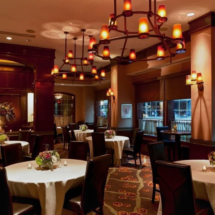 Pre-Function Meeting Room featuring round tables with white cloths & dark chairs and hanging chandeliers at Warwick New York