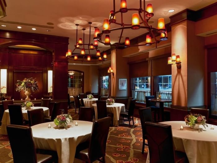 Pre-Function Meeting Room featuring round tables with white cloths & dark chairs and hanging chandeliers at Warwick New York