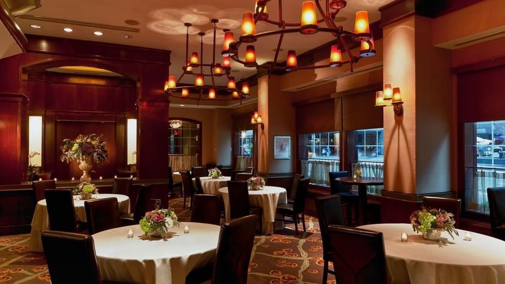 Pre-Function Meeting Room featuring round tables with white cloths & dark chairs and hanging chandeliers at Warwick New York