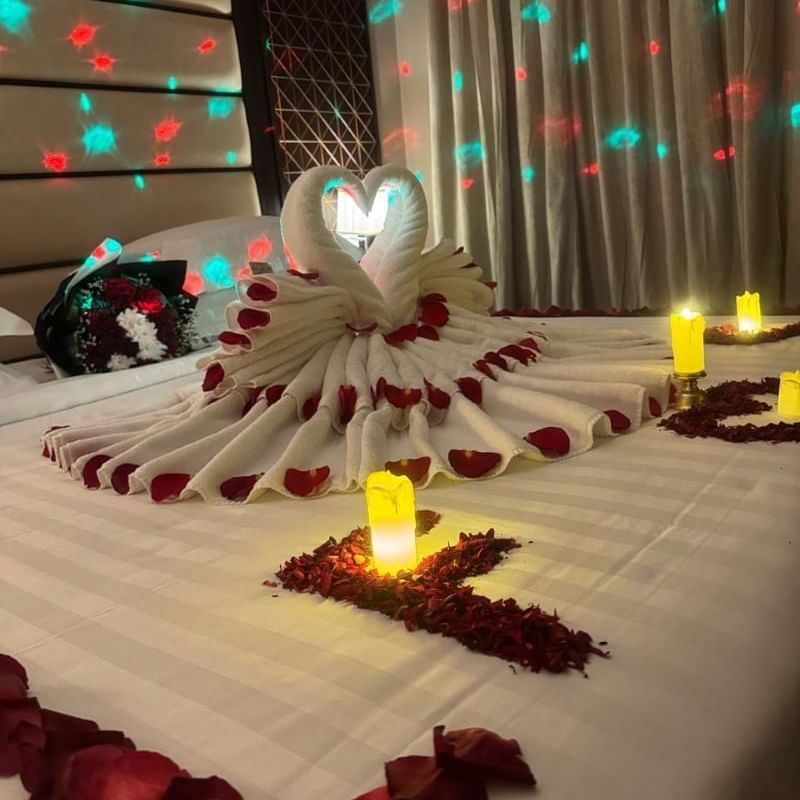 Room at Warwick Hotels and Resorts, decorated for a romantic evening with rose petals, candles, and a towel swan on the bed