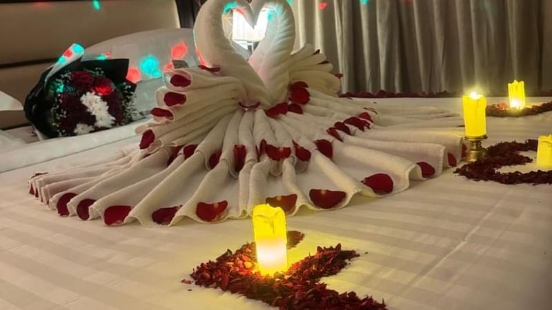 Room at Warwick Hotels and Resorts, decorated for a romantic evening with rose petals, candles, and a towel swan on the bed