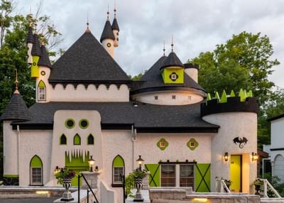 A whimsical castle with green accents, spires, and a playful design under a cloudy sky at The Roxbury