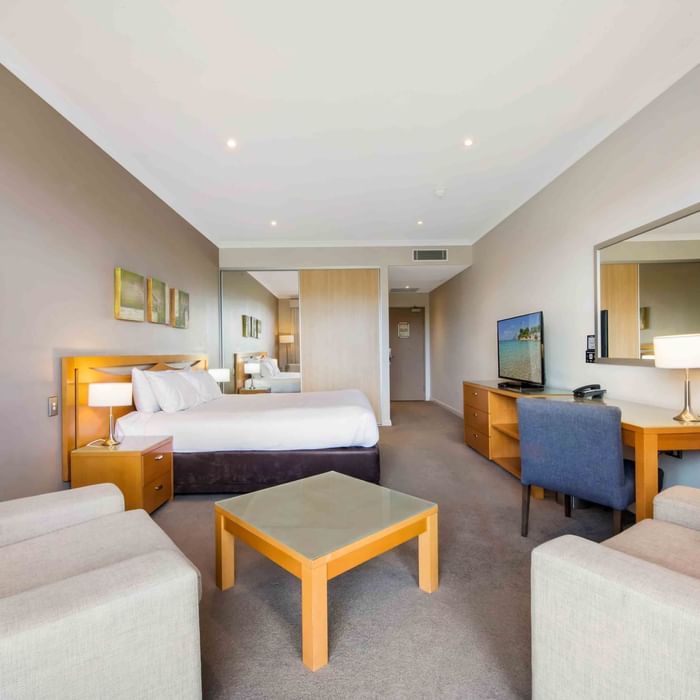 Deluxe Golf View Room with a large bed, sitting area, desk, TV, and reflective wall mirror at Mercure Kooindah Waters