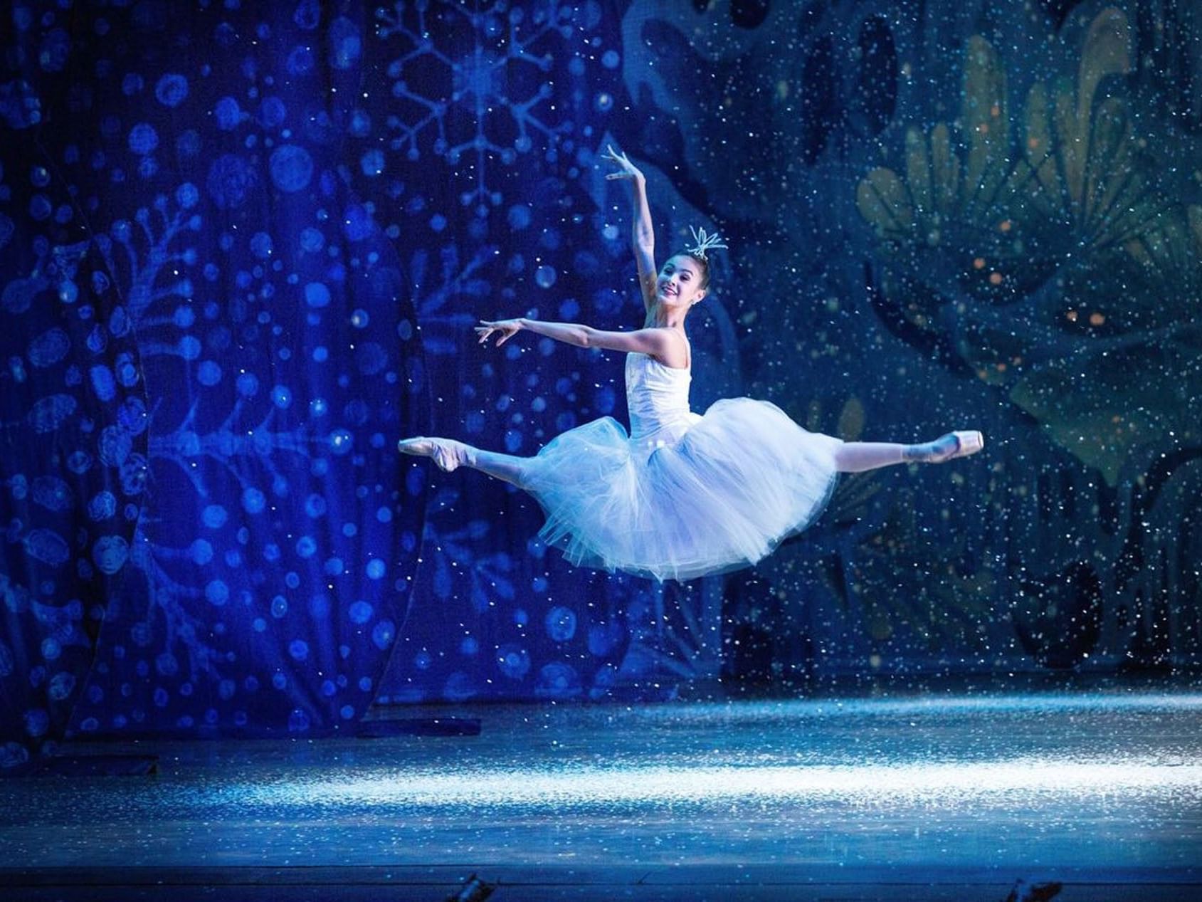 Ballerina performing on a stage with a sparkling blue backdrop in Miami City Ballet near Tradewinds Apartment Hotel