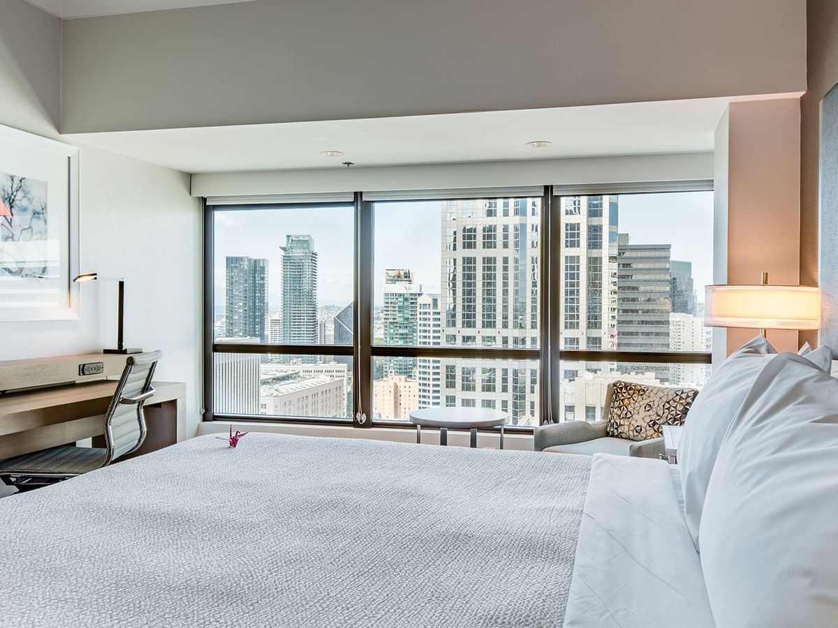 Hotel guestroom with king bed, desk, and a view of Seattle