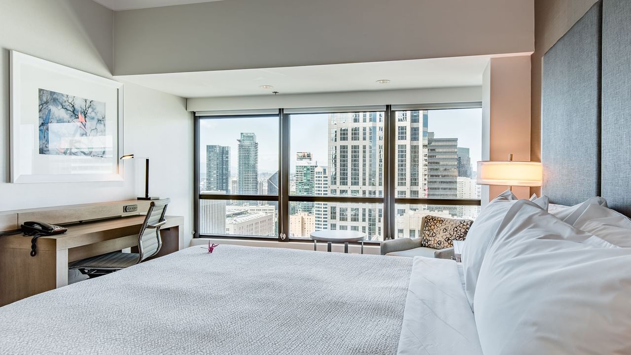 Hotel guestroom with king bed, desk, and a view of Seattle