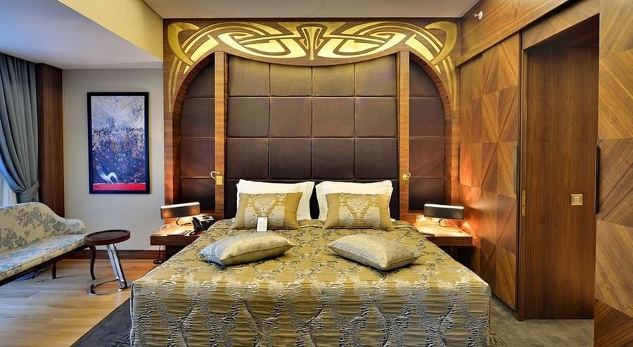 Gold patterned bed by a sofa under an ornate carved headboard in Ankara Suite with Terrace at Warwick Ankara