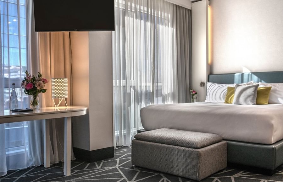 Bed with ottoman & hanging TV near window in Loft Suite at Warwick Le Crystal Montreal