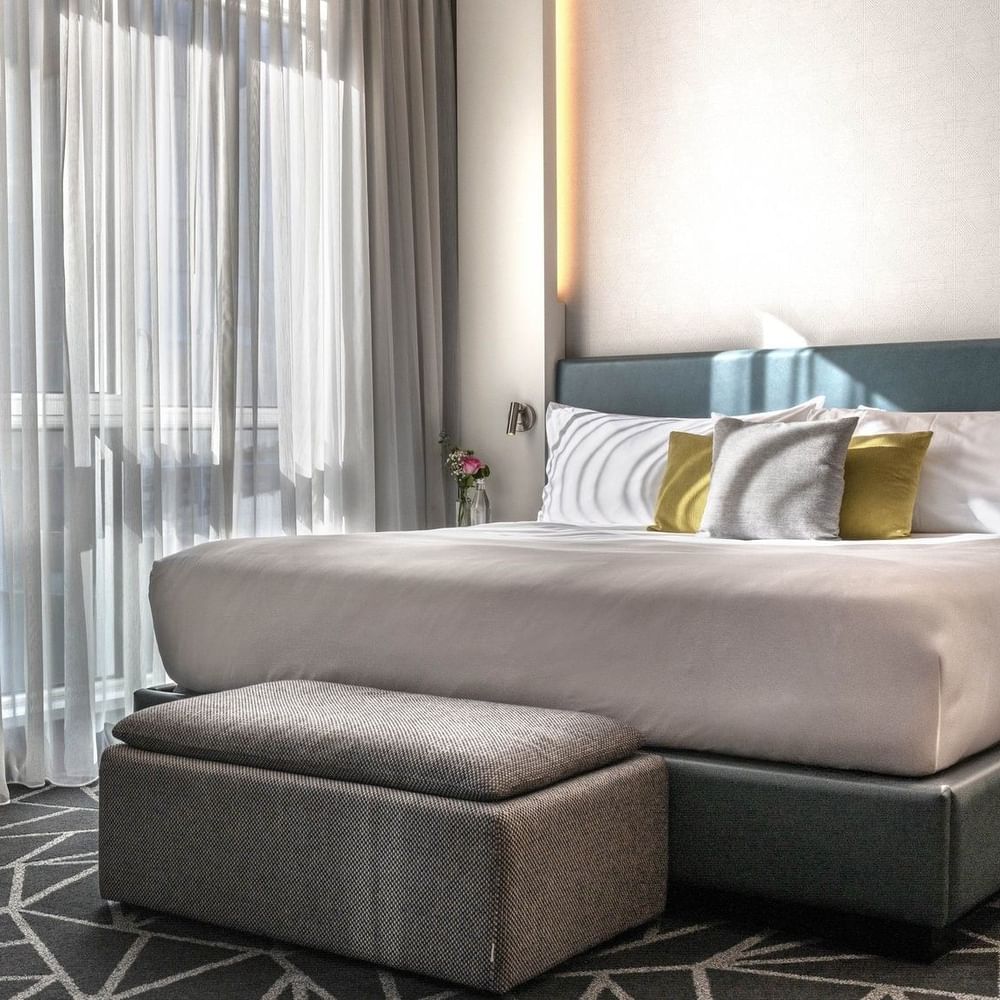 Bed with ottoman & hanging TV near window in Loft Suite at Warwick Le Crystal Montreal