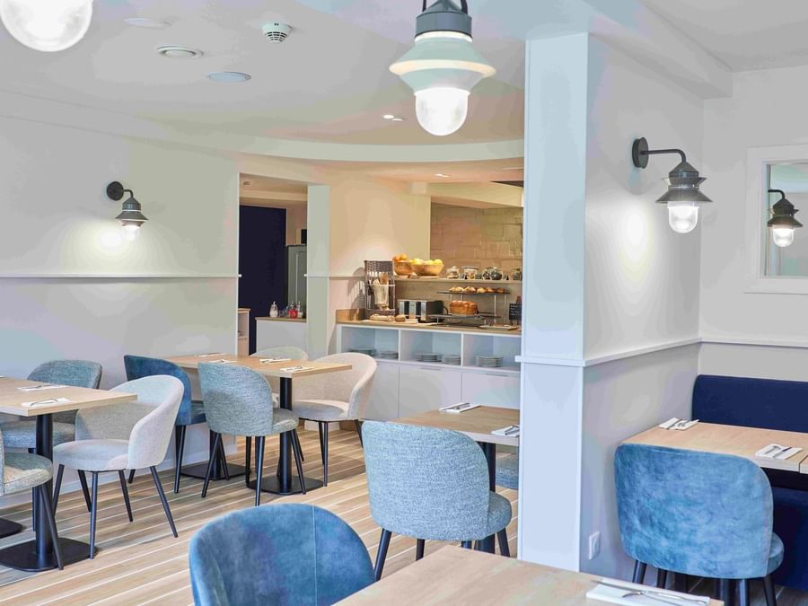 Salle à manger élégante avec tables et chaises bleues à l'Hôtel La Marébaudière.
