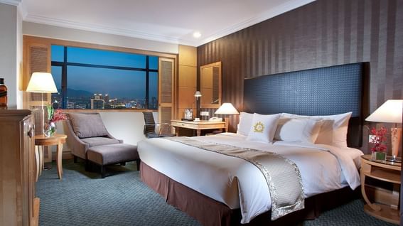 King-size bed with a cozy lounger in Crystal Club Room at Grand Park Wuxi