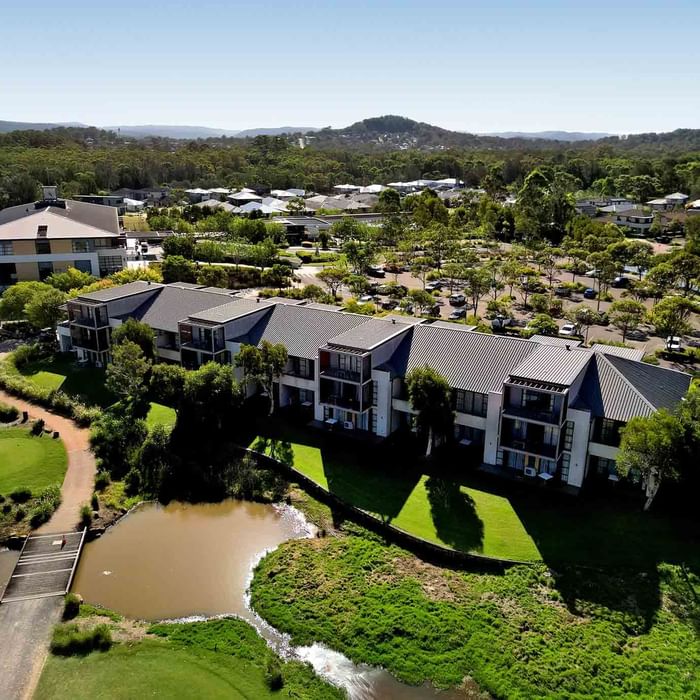 Aerial view of Mercure Kooindah Waters with a pond, and a parking lot surrounded by greenery