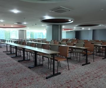 Yerbabuena Room with rows of tables and beige chairs beneath circular lights at Unika Hotels, an elite Bogota hotel