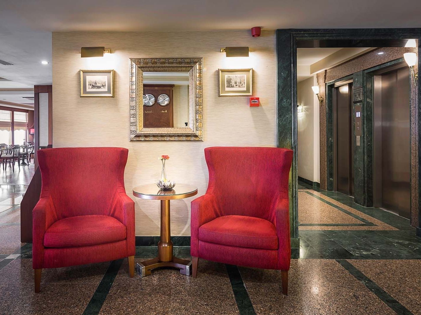 The lobby area with Two armchairs and a round side table at Titanic Comfort Sisli Lobby