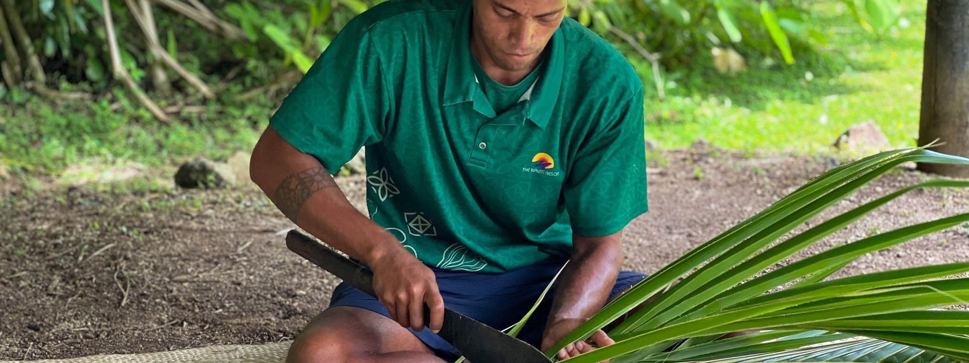 Man weaving palm leaves with a machete at The Naviti Resort in Korolevu