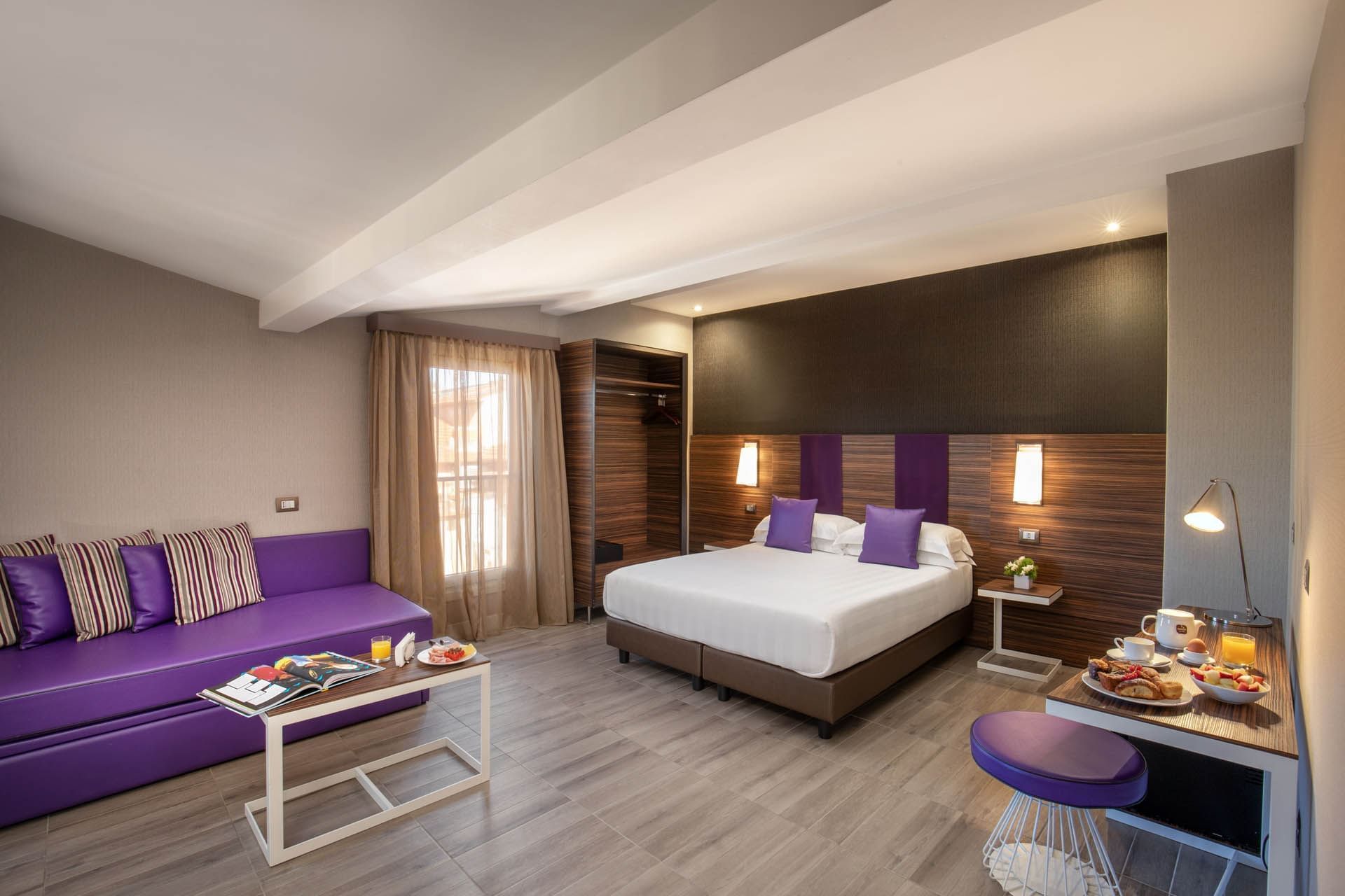Family Room at The Republic Hotel featuring a cozy bed with night lamps by the window, a lounge area, and wooden floors