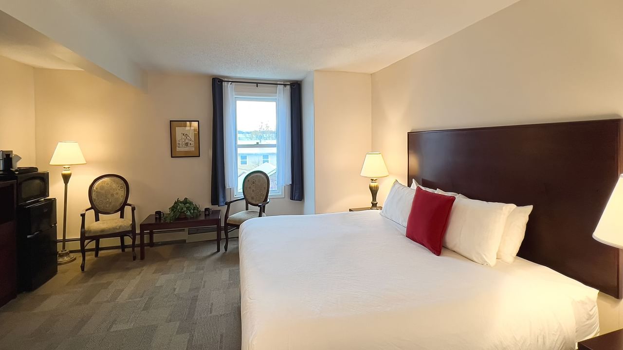 Bedroom suite with bed, window, chair, tv, minifridge, and table
