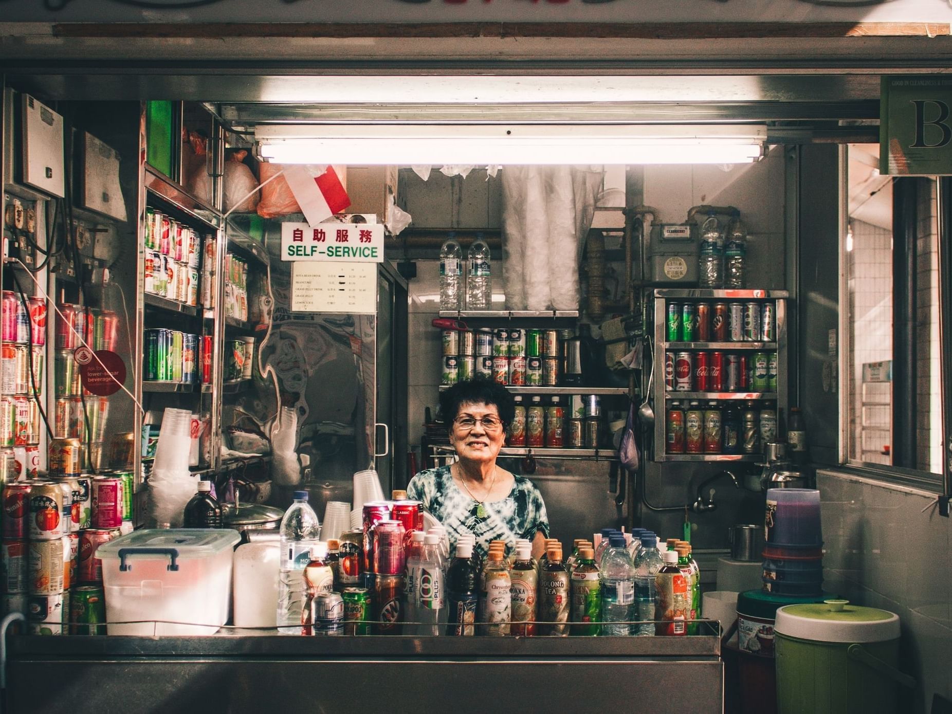 Woman behind a counter with bottles of beverages at Momentus Hotel Alexandra