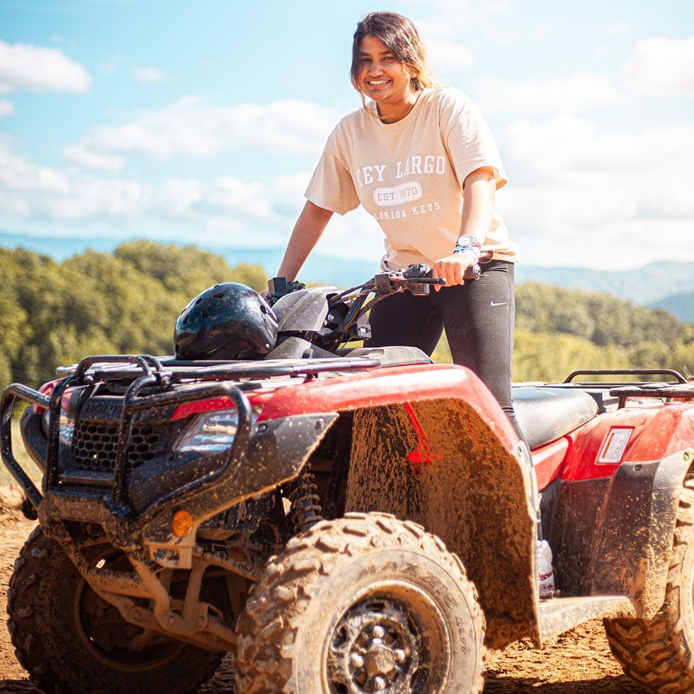 A person standing on a muddy quad bike with a helmet near Falkensteiner Hotel Prague