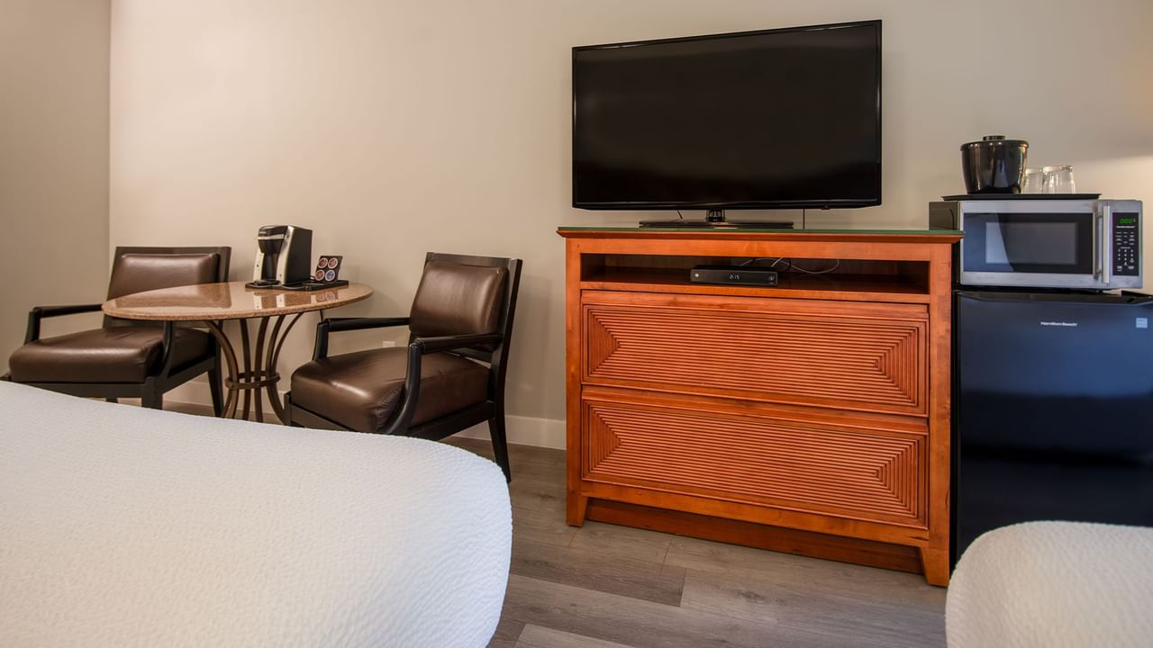 Hotel guestroom with two queen beds, TV, microwave, mini fridge, table and chairs