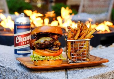 Burger and fries on a wooden board with a beer can in Harbor Bistro Terrace at Portland Harbor Hotel