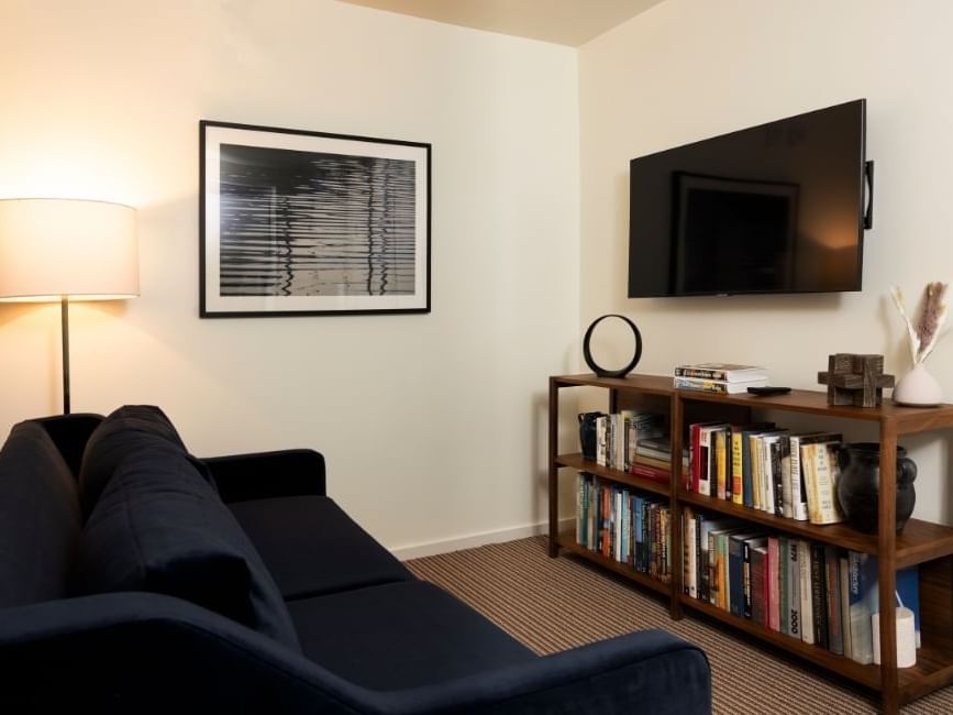 LED TV and a bookshelf featuring a cozy lounger in University Suite at The Study Hotel at Johns Hopkins
