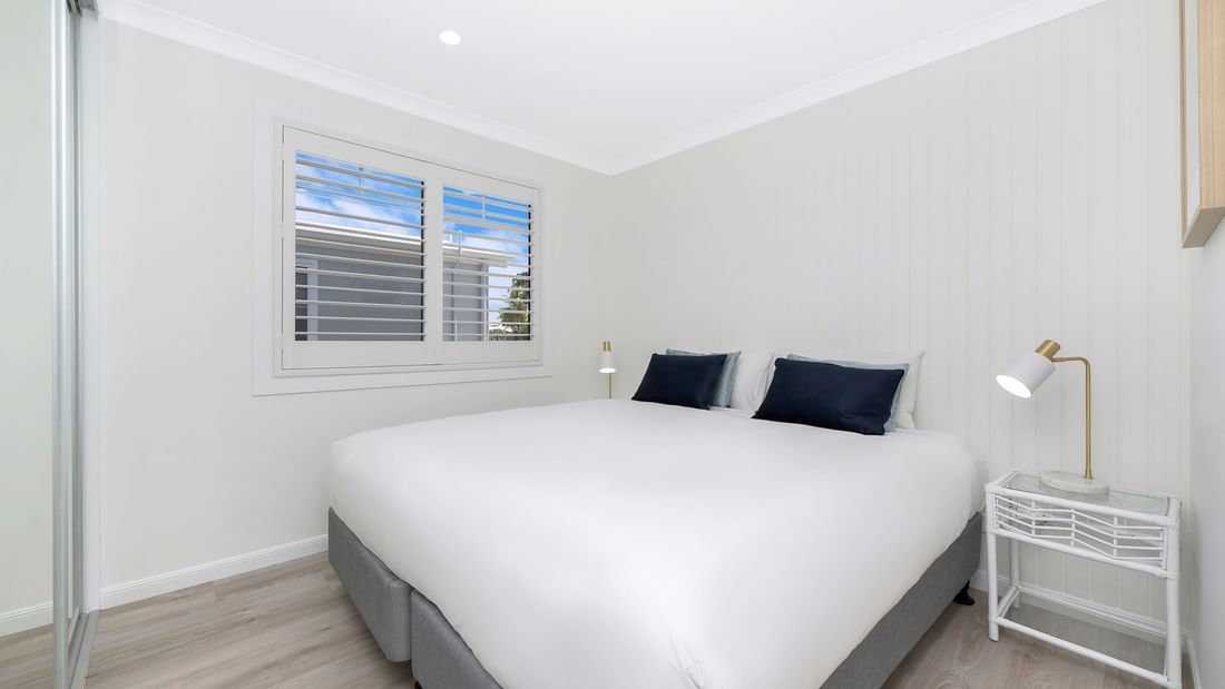 Deluxe Bungalow 2 Bedroom featuring a large bed with pillows, a bedside table, and a window at Mercure Hotel Townsville