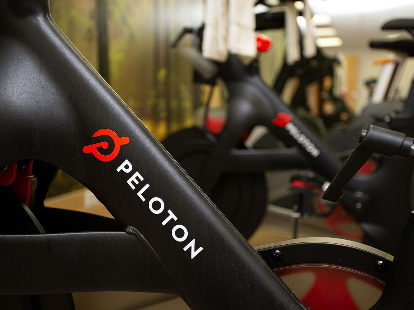 Peloton bike with logo in a gym with other bikes and towels.