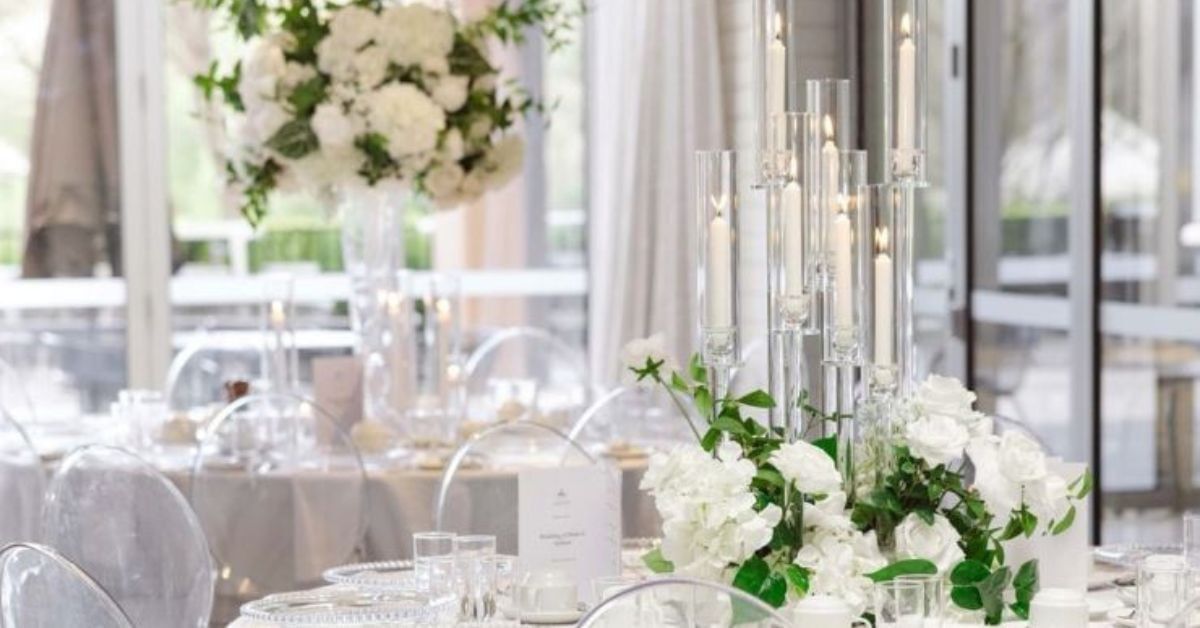 Wedding reception setup with white floral decor and tall glass candle in Event Pavilion at Amora Herencia Riverwalk Melbourne