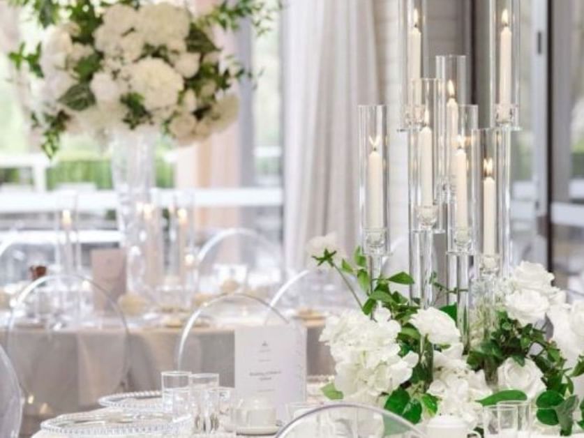 Wedding reception setup with white floral decor and tall glass candle in Event Pavilion at Amora Herencia Riverwalk Melbourne