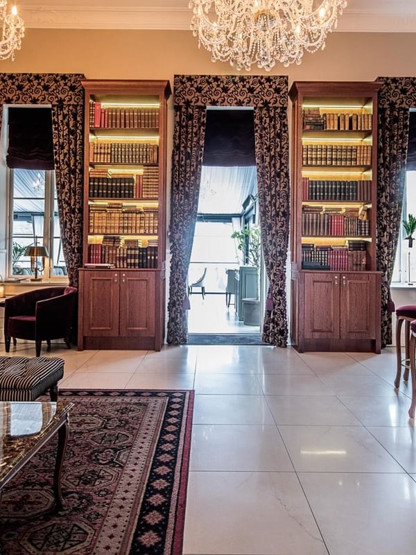 Elegant The Library Bar with bookshelves, chandeliers, and cozy seating at Kokkedal Slot Copenhagen by Warwick in Hørsholm.