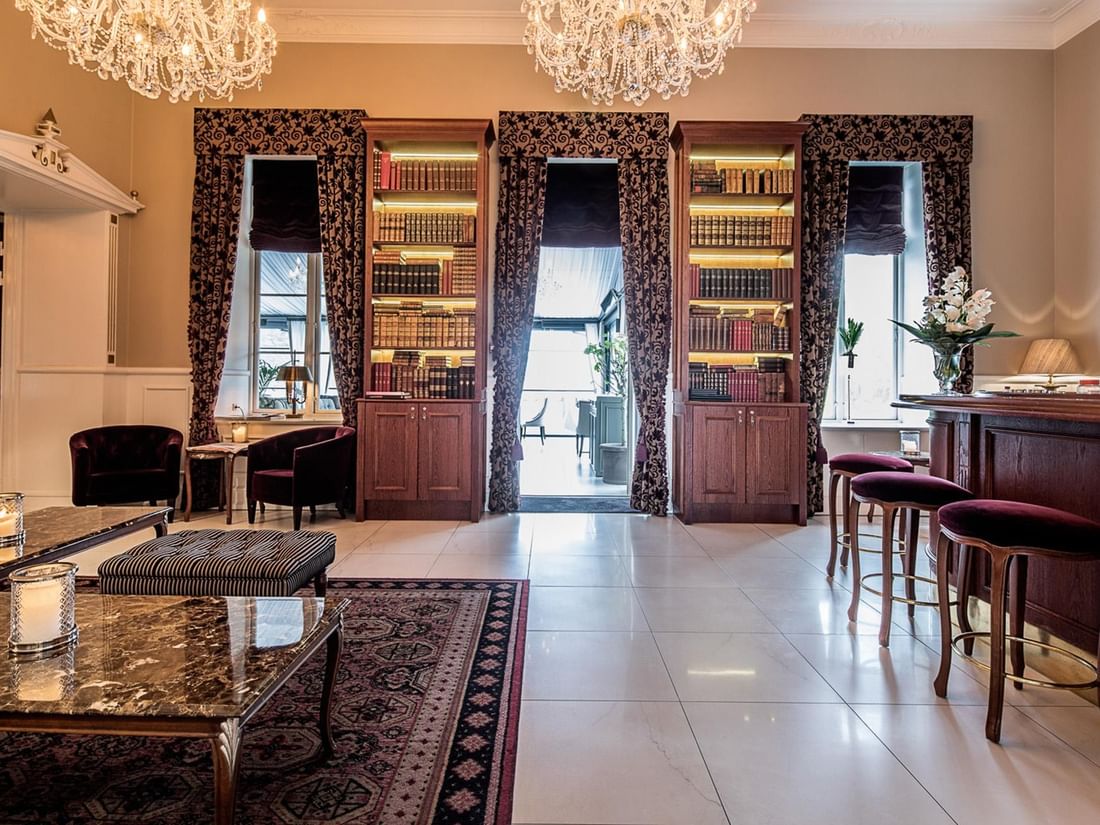Elegant The Library Bar with bookshelves, chandeliers, and cozy seating at Kokkedal Slot Copenhagen by Warwick in Hørsholm.