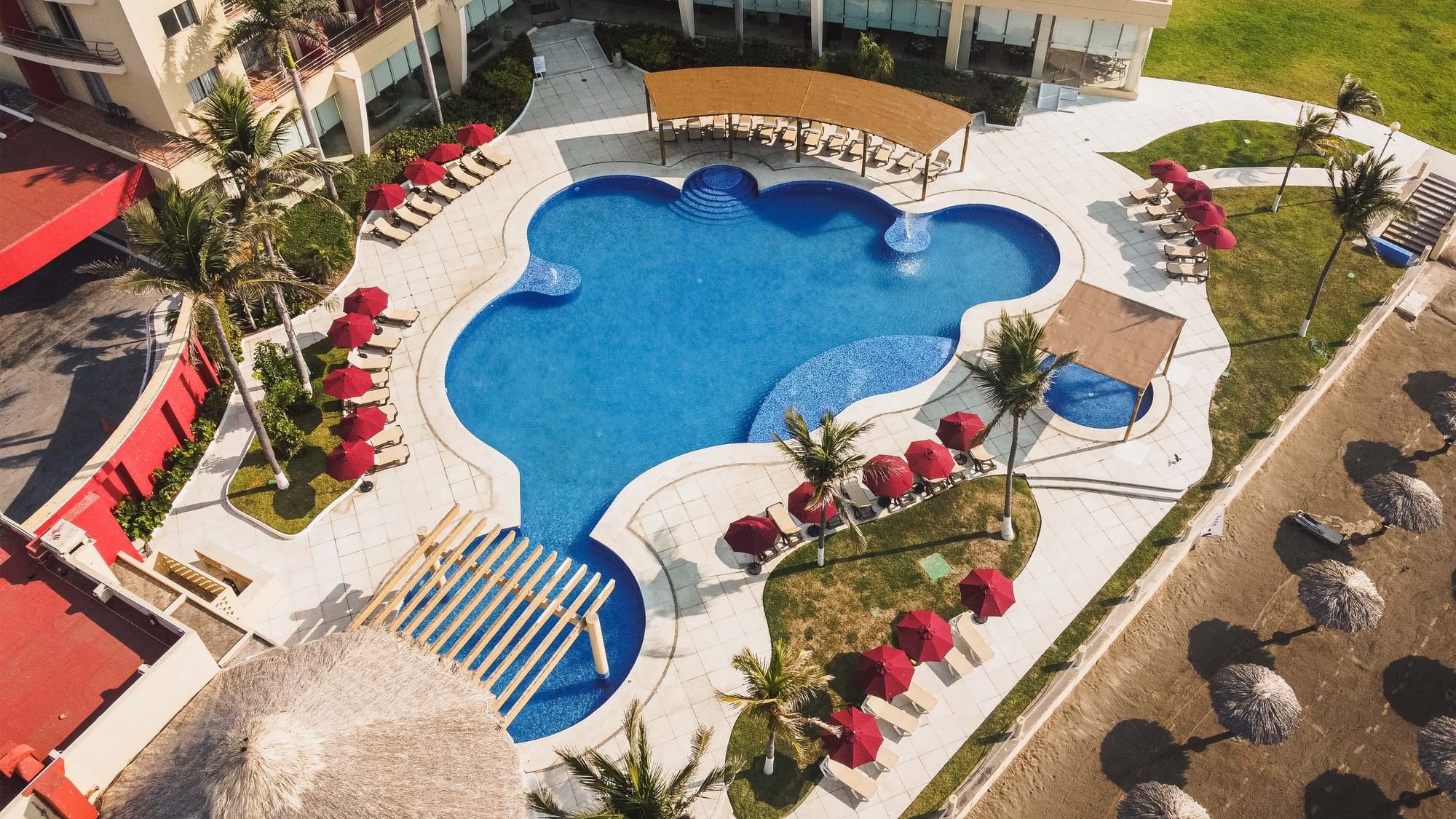 An aerial view of an outdoor pool with surrounding lounge chairs and umbrellas at Camino Real Veracruz