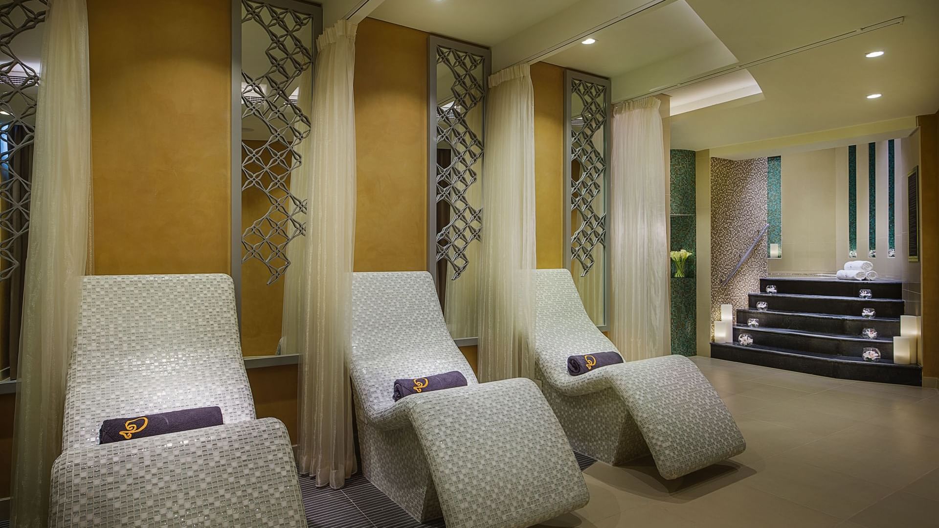 Curved spa beds with towels in The Distinction Spa Relaxation area at DAMAC Maison