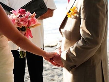 Novios tomados de la mano en la orilla de la playa durante su boda cerca de Los Altos Resort