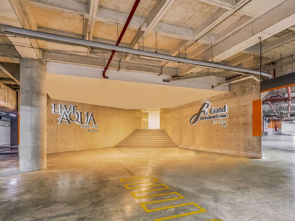Indoor basement parking & stairway at the hotel with sign featuring Live Aqua Resorts and Residence Club